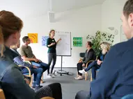 Eine junge Fachkraft hält einen Vortrag vor einer Gruppe